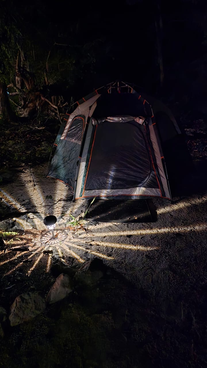 A camping tent at night lit by pathway lights.